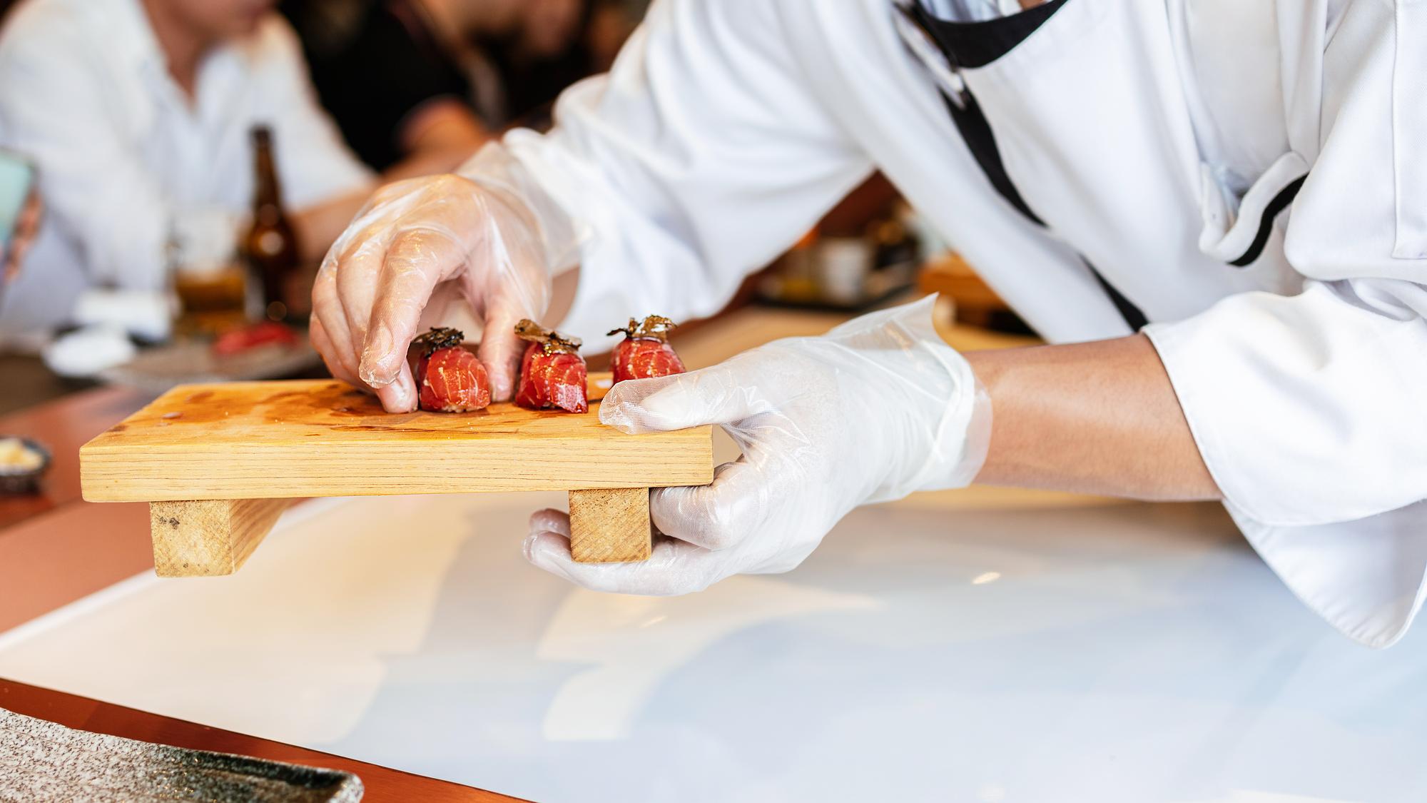 Workshop kitchen with chefs at bench preparing simple plated dishes